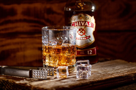 Whisky Still Life: A bottle and glass of Chivas Regal on a textured wooden board