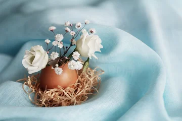White flowers in eggshells on blue fabric. Easter home decoration. © smiltena