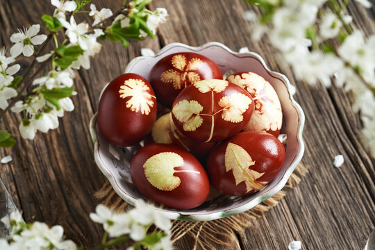 Brown Easter egg dyed with onion peels with a pattern of fresh leaves in a bowl
