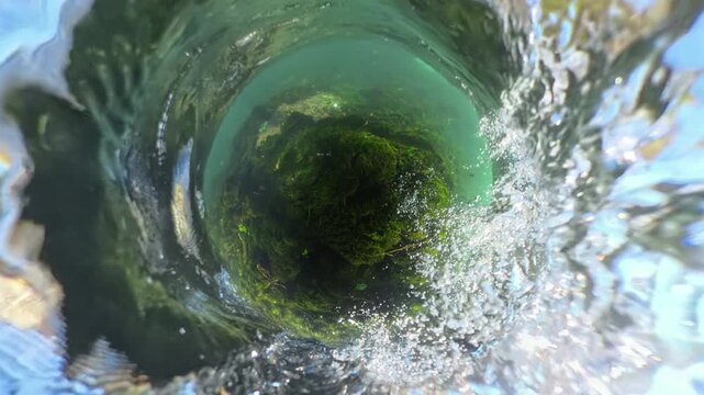 gives the sensation of being swept downstream in a turbulent river, with a spherical distortion effect and underwater rocks covered in moss, creating a dynamic and immersive experience.