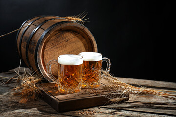Mugs with fresh beer, spikes and barrel on wooden table against black background, space for text