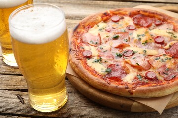 Obraz premium Yummy pizza and glasses of beer on wooden table, closeup