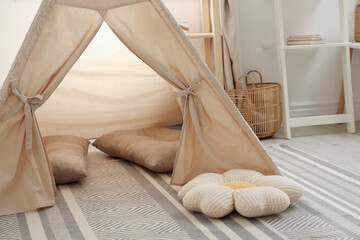 Stylish toy wigwam and pillows on floor in playroom. Interior design © New Africa
