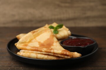 Tasty crepes with mint leaves and jam served on wooden table, closeup © New Africa