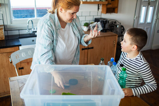 Mother and son sorting recyclables in kitchen at home