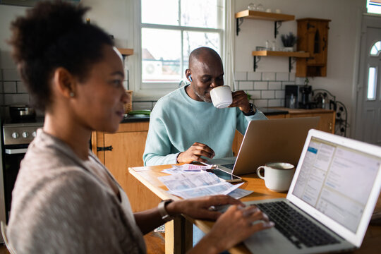 Couple paying bills on laptops at kitchen table