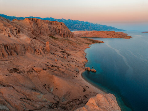 Rucica beach in Metajna on Pag island curved shoreline, crystal-clear turquoise sea, sunlit barren terrain and rocky Adriatic sea