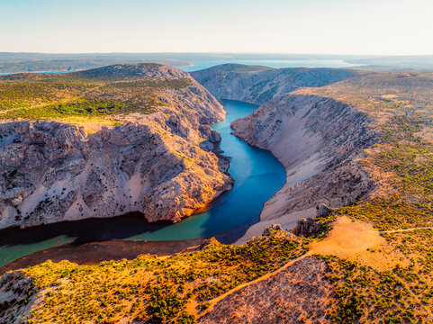 View of the Zrmanja River Canyon in Croatia, with winding turquoise waters cutting through limestone cliffs. A scenic natural wonder popular for kayaking and hiking