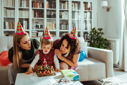 Family celebrating toddler's third birthday at home