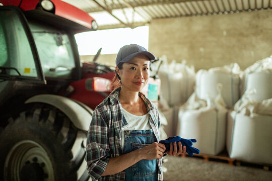 Woman farmer by tractor in farm warehouse