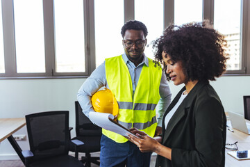 Business Meeting Between Engineer and Project Manager in Office With Hard Hat and Plans