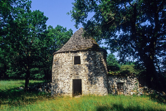 Dry stone hut in Quercy area surrounded by trees and grass in Midi-Pyrenees region of France