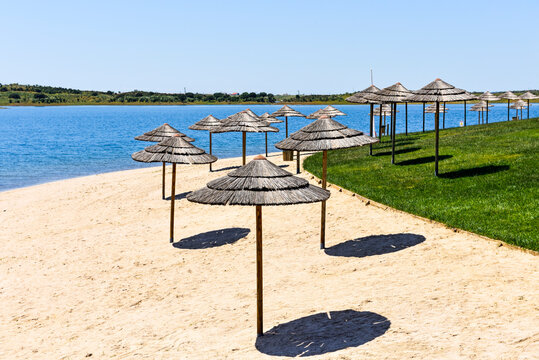 Visitors relax under umbrellas at Mourao beach on Alqueva lake in Portugal during sunny weather