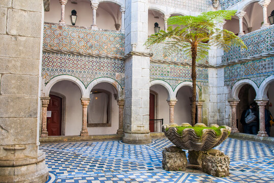 Cloister featuring patterned tiles and a palm tree in Pena National Palace, a notable landmark in Sintra, Portugal