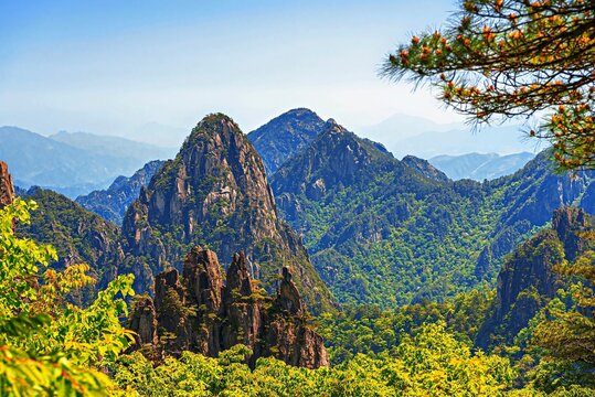 Huangshan in Anhui Province shows mountain peaks and green forests with clear skies under bright sunlight