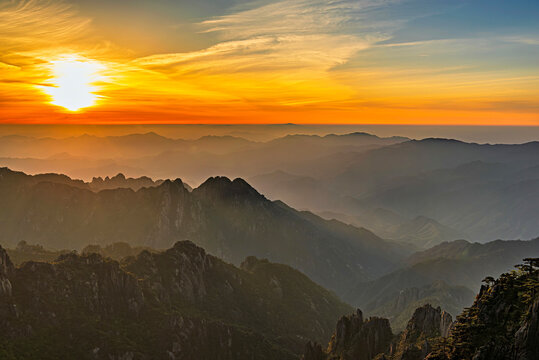 Sunrise over Huangshan Mountain showcasing layers of hills and a bright sky in Anhui Province, China
