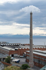 Fototapeta premium Coastal view with a tall industrial brick chimney, factory buildings. Savona, Italy
