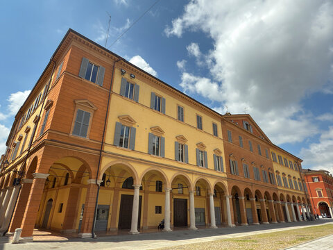 Visit to Piazza Roma in Modena: Colorful houses and porticos under blue skies in Emilia Romagna