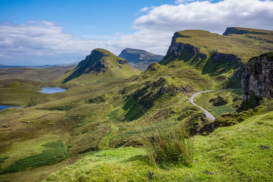 Narrow road winds through rugged hills at Trotternish escarpment on the Isle of Skye in Scotland during daytime