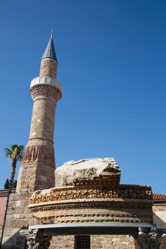 Roman ruin with inscription and minaret stand together in Kaleici Antalya Turkey under clear blue sky