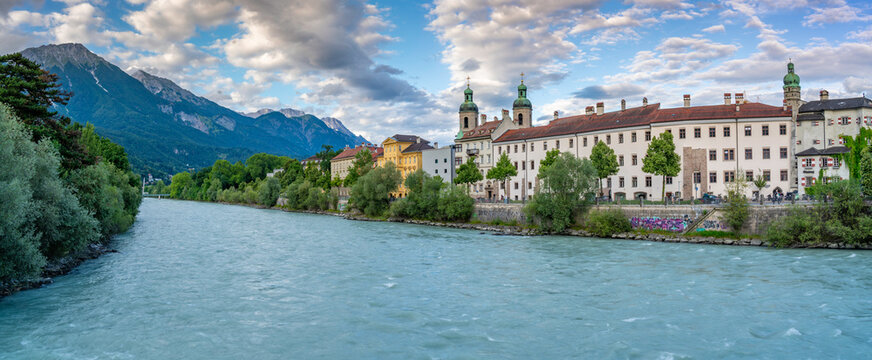 View of St. Jakob Cathedral and colorful buildings by River Inn at golden hour in summer in Innsbruck, Tyrol Region, Austria