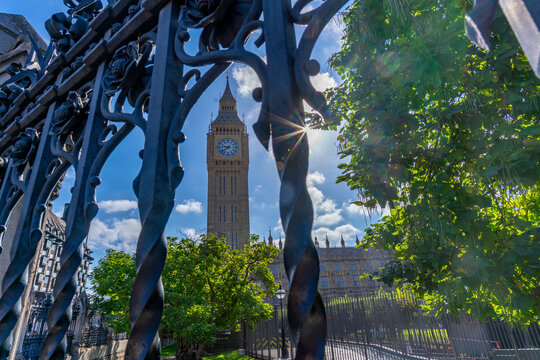 View of Big Ben clock tower surrounded by trees and sunlight in Parliament Square during summer in Westminster, London, United Kingdom