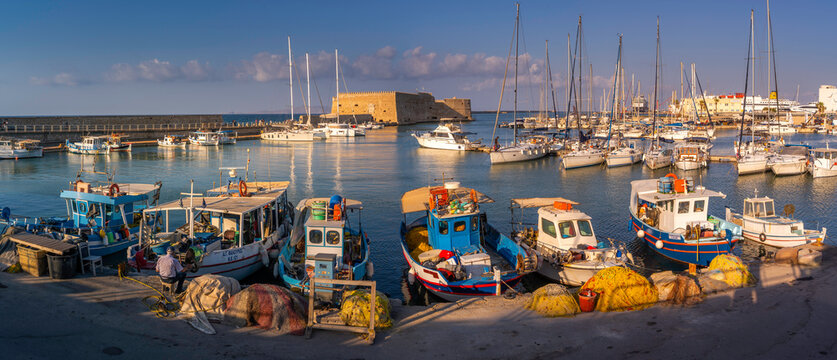 View of Koules Venetian Fortress and boats in Heraklion Port at sunset in Crete, Greece, showing daily life and port activity