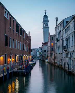 Quiet waters reflect buildings at dusk along a canal in Venice, showing the city&acirc;&euro;&trade;s architecture and tower