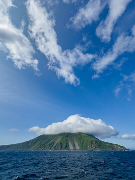 Stratovolcano rises on Kagamil Island in the Aleutian Archipelago of Alaska with green slopes and blue skies