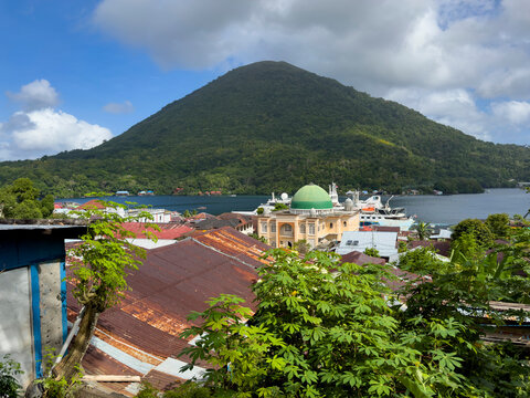 View of the harbor and buildings of Banda Neira with a mountain backdrop on the island in Indonesia
