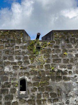 Fort Belgica features a weathered stone wall with a cannon pointing skyward