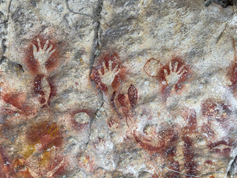 Rock art depicting handprints and figures on limestone cliffs in Berau Bay Papua Indonesia