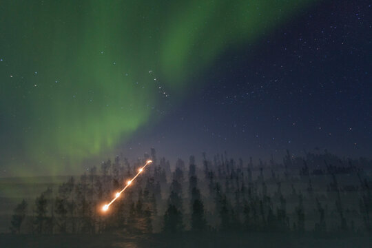 Bright colors of aurora borealis dance over boreal forest at Great Slave Lake during night in Northwest Territories, Canada