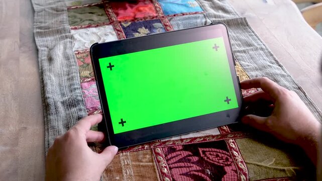 Close up of woman hands using a digital tablet with green screen chroma key and tracking markers for mobile app presentation outdoors during a sunny day at a resort villa