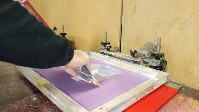 The master craftsman is using the siography technique to print tube designs onto the door of his cabinet.