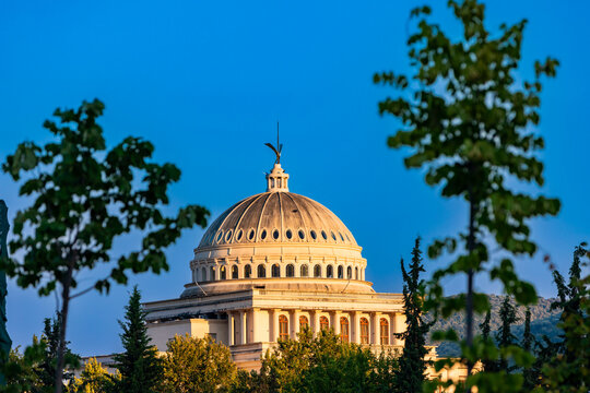 Sunset view of the domed roof of Resurrection of Christ Orthodox Cathedral in Berat framed by trees in Albania