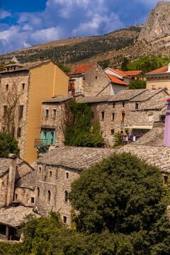 Close-up view of stone buildings and slate roofs in Old Town Mostar with colorful accents and historic features against a hillside