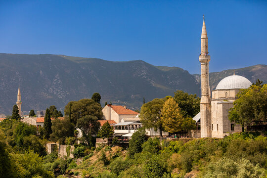 Koski Mehmed Pasha Mosque stands tall in Mostar with Dinaric Alps in the background under bright blue sky