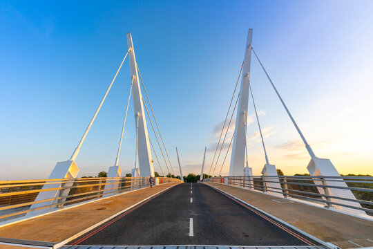 Twin-swing cable-stayed bridge connects two sides in Glasgow during sunset hours