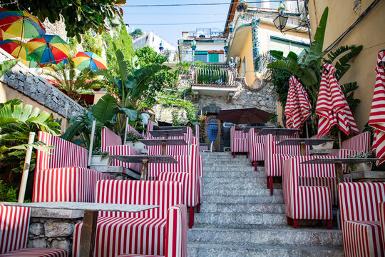 Charming outdoor seating area in historic old town Taormina with colorful umbrellas and striped chairs in Messina region of Italy