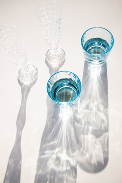 Vintage water and champagne glasses casting shadows in sunlight in Italy