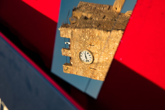 Historic clock tower reflected in modern surface in Taormina, Messina region of Sicily