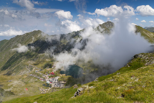 Fagaras mountains and Balea lake in Romania with clouds and greenery visible in the landscape
