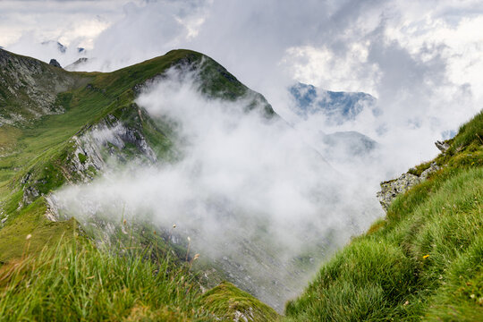 View of Fagaras mountains with Balea lake in Romania showing clouds and grass
