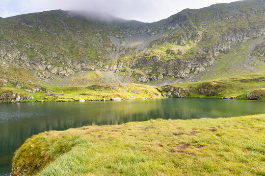 Exploration of Capra Lake surrounded by Fagaras Mountains in Romania on a cloudy day