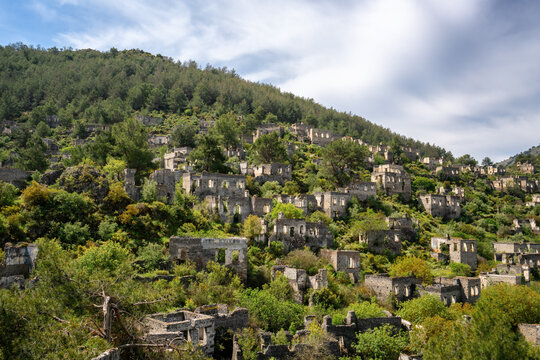 Exploring the abandoned houses of Kayakoy ghost town surrounded by mountains and vegetation in Turkey