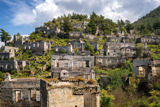 Abandoned houses in Kayakoy ghost town nestled in mountains and lush vegetation in Fethiye Turkey