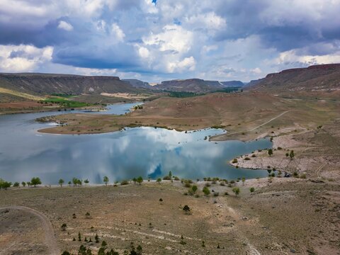 Drone view of Akkoy dam lake showing reflection on water in Cappadocia region of Turkey with hills and land around the lake