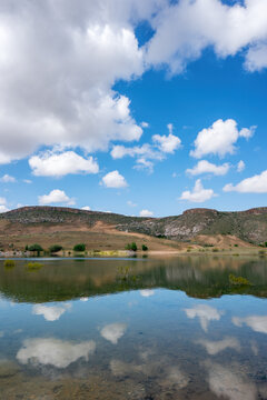 Beautiful landscape at Akkoy dam lake in Cappadocia with clear water reflection and blue sky full of clouds
