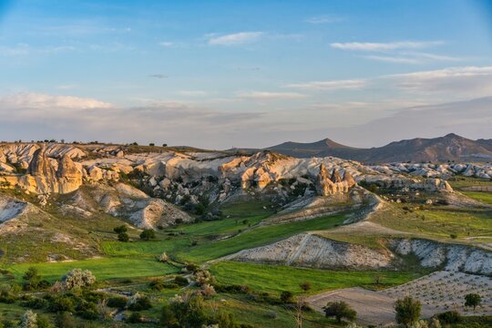 Sunrise over rock formations in Love valley near Cappadocia showing unique shapes and surrounding green land